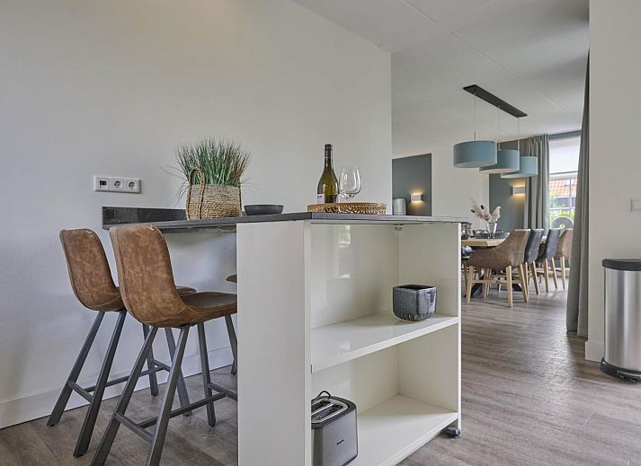 Charmante gevel van Sea Deluxe vakantiewoning in Colijnsplaat, Noord-Beveland, omgeven door bloeiende bloemen en rustige straat.