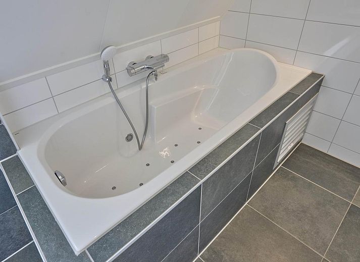 Detail van een knus kussen op de bank in Sea Deluxe vakantiehuis, Colijnsplaat, Noord-Beveland, voor een huiselijke sfeer.