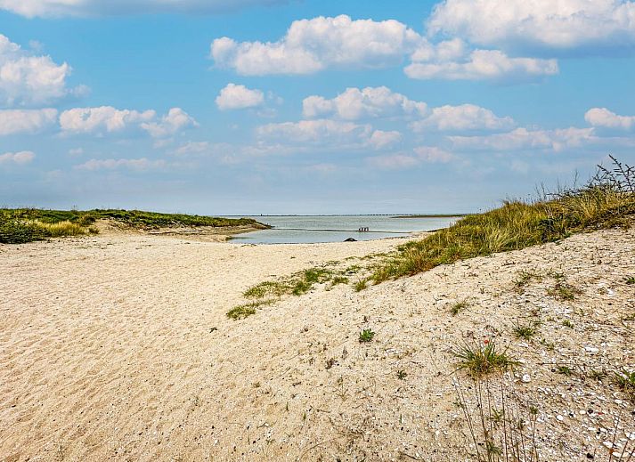Ess- und Wohnbereich im Ferienhaus Perfektion am Strand, Colijnsplaat, mit grossem Tisch und stimmungsvoller Beleuchtung.