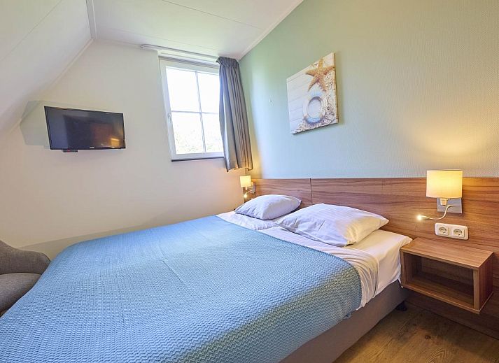 Knusse open haard en luxe fauteuil in vakantiehuis Ocean Ease 49, gelegen in Colijnsplaat, Noord-Beveland.