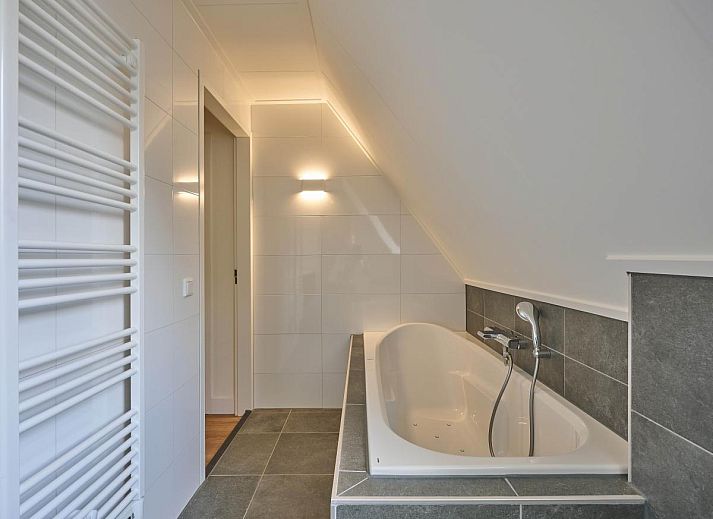 Knusse open haard en luxe fauteuil in vakantiehuis Ocean Ease 49, gelegen in Colijnsplaat, Noord-Beveland.