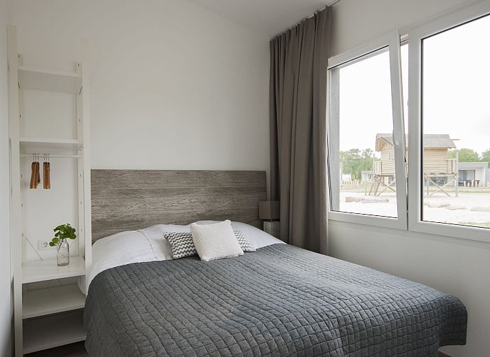 Gemuetliches Wohnzimmer von Bungalow de Dukdalf in Kamperland, mit bequemer Sitzecke und grossen Fenstern.