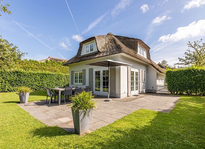 Villa R8B in Kamperland, Noord-Beveland biedt een charmant vakantiehuis met rieten dak en zonovergoten terras in groene omgeving.