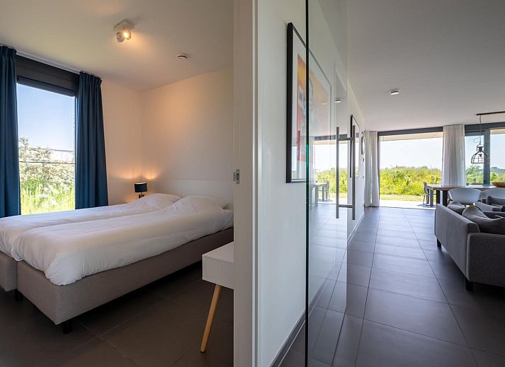 Ruime eetruimte in Duinvallei 39, De Groote Duynen, Kamperland, met moderne stoelen en een glazen wand.