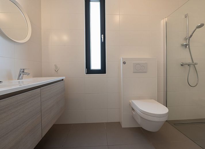 Lichte woonkamer in Duinvallei 24 | De Groote Duynen, vakantiehuis in Kamperland, met comfortabele bank en tuinzicht.