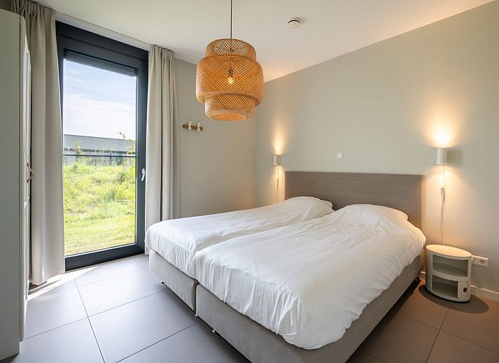 Lichte woonkamer in Duinvallei 24 | De Groote Duynen, vakantiehuis in Kamperland, met comfortabele bank en tuinzicht.