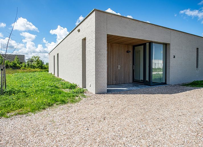 Open dining room in Duinvallei 38 | De Groote Duynen, Kamperland, with wooden table and designer chairs.