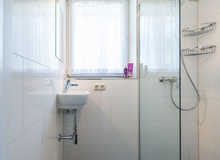 Gemuetliches Wohnzimmer in der Leeuwerikenlaan 15, De Banjaard, Kamperland mit grossen Fenstern und bequemen roten Sofas.