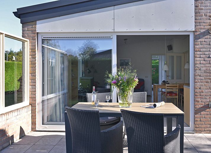 Sonniger Garten mit Terrasse und Sonnenschirm im Ferienhaus Saturnuslaan 14 Rancho Grande in Kamperland, Noord-Beveland, Zeeland.