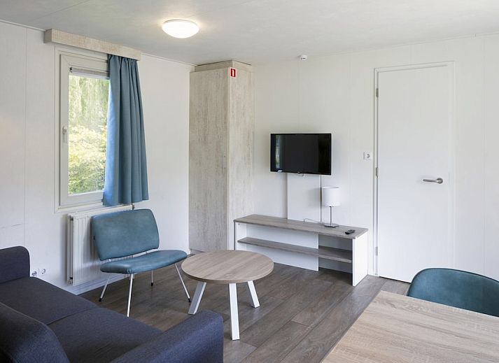 Gezellige woonkamer in chalet RP4B, Kamperland, met moderne keuken en strandthema muurdecoratie.
