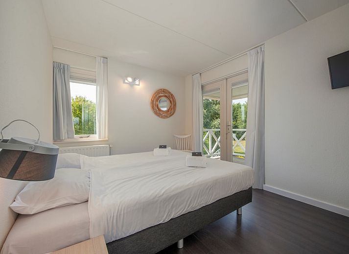 Geraeumiges Wohnzimmer der Villa R10B in Kamperland, Noord-Beveland, Zeeland mit moderner Einrichtung und Blick auf die gruene Umgebung.