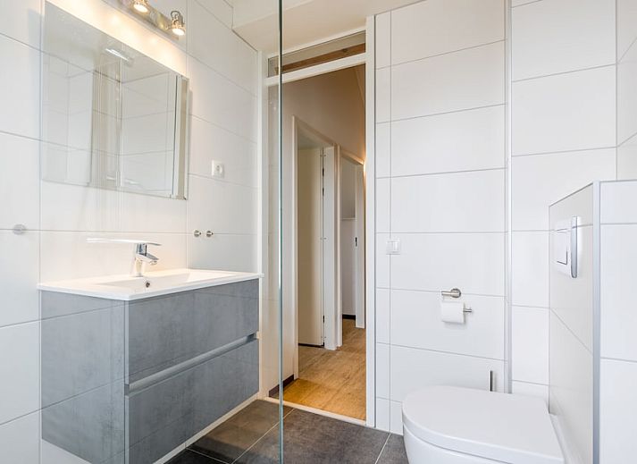 Gezellige woonkamer in Villa 4A, vakantiehuis in Kamperland, Zeeland. Comfortabele zithoek met uitzicht op de groene tuin.