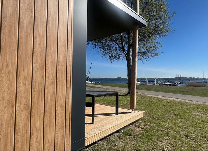 Chalet de Golfbreker in Kamperland, Noord-Beveland, Zeeland mit moderner Veranda und gruener Umgebung.