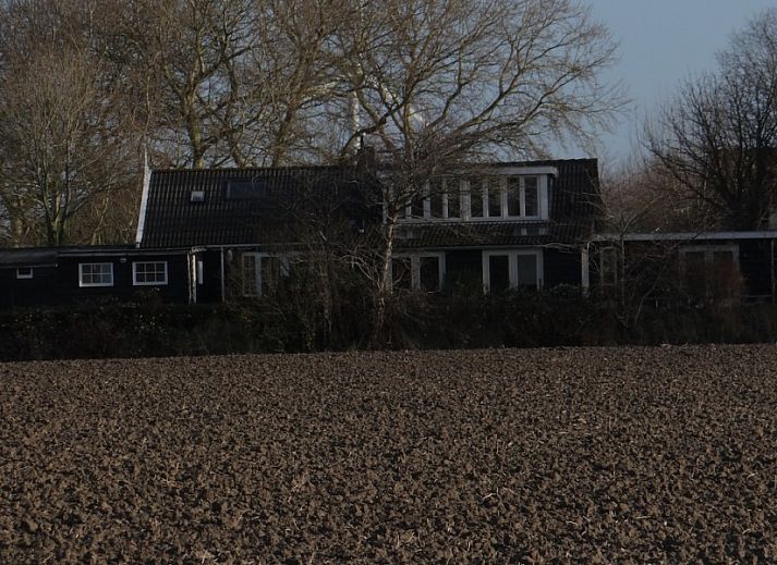 Charmantes Strandhaus De Bakkeete in Kamperland, Zeeland, mit Blick auf gruene Felder und einem einladenden Eingang.