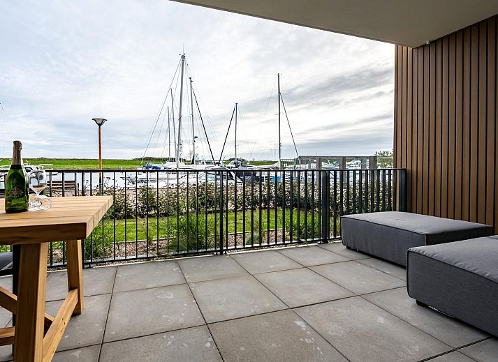 Moderne zithoek in vakantiehuis Harbour Loft 1E, Noord-Beveland, met uitzicht op zeilboten.