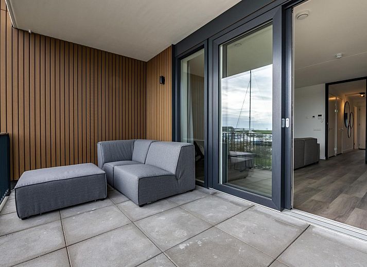 Moderne zithoek in vakantiehuis Harbour Loft 1E, Noord-Beveland, met uitzicht op zeilboten.