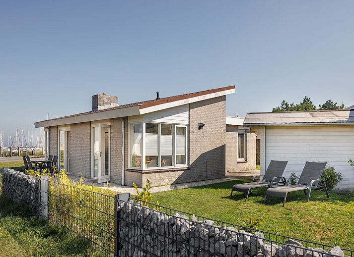 Helles Esszimmer im NA-Bungalow, Kamperland, Noord-Beveland, mit Blick auf den gruenen Garten und viel Fenster fuer natuerliches Licht.