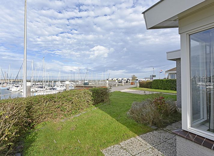 Blick auf den Yachthafen vom Einfamilienhaus in Kamperland, Ferienhaus in Noord-Beveland, Zeeland mit grnem Garten und blauem Himmel.