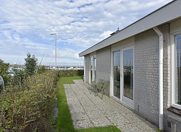 Blick auf den Yachthafen vom Einfamilienhaus in Kamperland, Ferienhaus in Noord-Beveland, Zeeland mit grnem Garten und blauem Himmel.