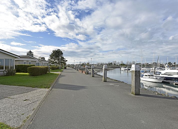 Blick auf den Yachthafen vom Einfamilienhaus in Kamperland, Ferienhaus in Noord-Beveland, Zeeland mit grnem Garten und blauem Himmel.