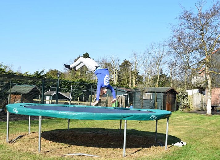 Kinderen springen op trampoline in de tuin van De Wulp, vakantiehuis in Burgh-Haamstede, Zeeland.