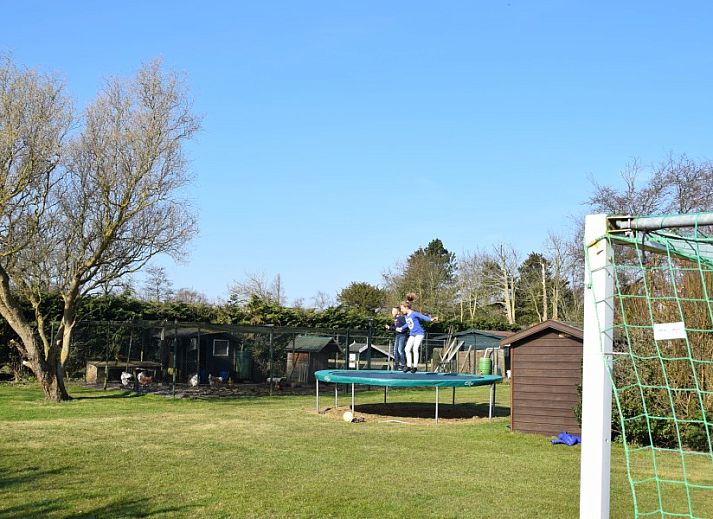 Kinderen springen op trampoline in de tuin van De Wulp, vakantiehuis in Burgh-Haamstede, Zeeland.