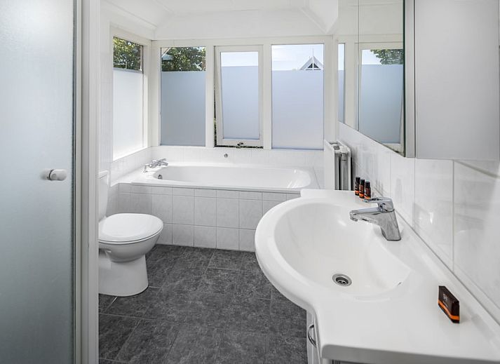 Ruime woonkamer van Buitenhuis Comfort 12, een vakantiehuis in Bruinisse, Schouwen-Duiveland, Zeeland, met comfortabele zithoek en uitzicht op de tuin.