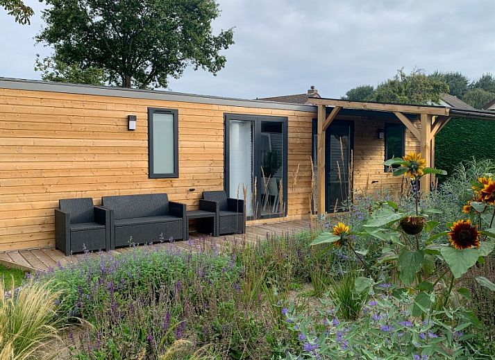 Verseputshofje chalet in Renesse, Schouwen-Duiveland, Zeeland met een uitnodigende veranda en weelderige tuinomgeving.