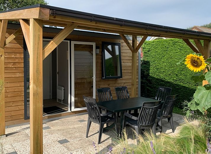 Verseputshofje chalet in Renesse, Schouwen-Duiveland, Zeeland met een uitnodigende veranda en weelderige tuinomgeving.