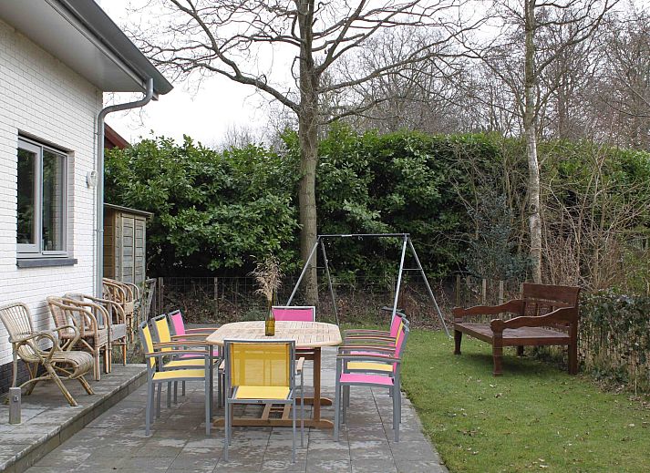 Terrace of Family House Bremweg 22 in Renesse, with wooden seating and surrounded by green nature.