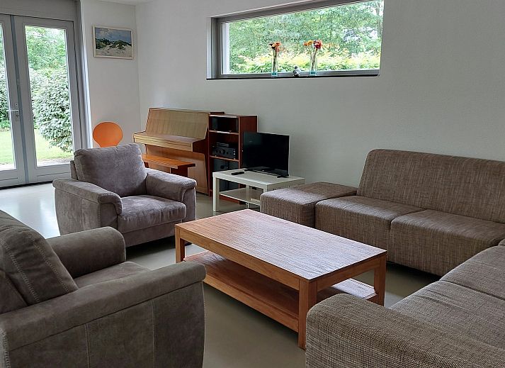Terrace of Family House Bremweg 22 in Renesse, with wooden seating and surrounded by green nature.