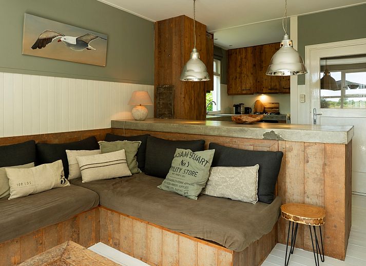 Blick von der Terrasse der Lodge to Lounge in Nieuw-Haamstede, mit Liegestuehlen und gruener Landschaft.