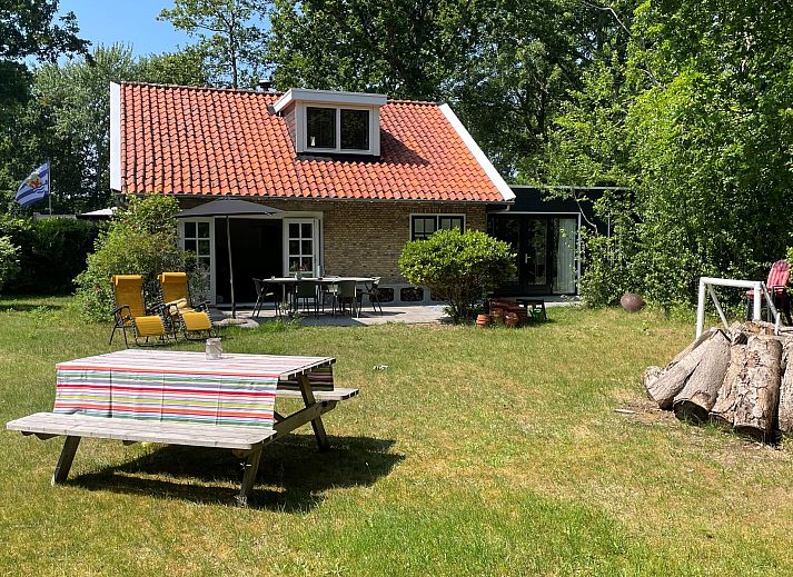 Terras van Vakantiehuis Populierenlaan 3 in Nieuw-Haamstede, Zeeland met tuinmeubilair en parasol.