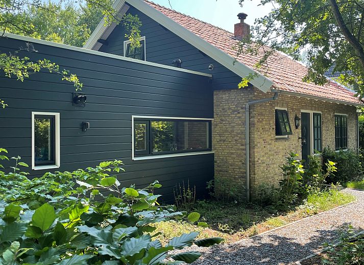 Terras van Vakantiehuis Populierenlaan 3 in Nieuw-Haamstede, Zeeland met tuinmeubilair en parasol.