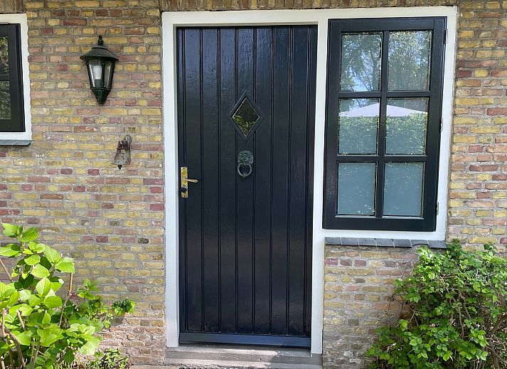 Ingang van Vakantiehuis Populierenlaan 3 in Nieuw-Haamstede, met houten trap en lichte deur.