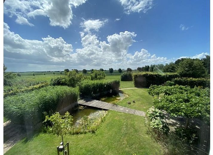 Aussenansicht des Ferienhauses in Dreischor, ein attraktives Ferienhaus in Schouwen-Duiveland, Zeeland, mit einem schoenen Garten und blauem Himmel.