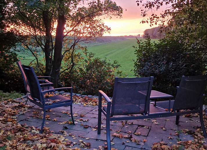 Groene oase bij Vakantiehuisje in Dreischor, Schouwen-Duiveland, Zeeland met bomen en tuinmeubilair.