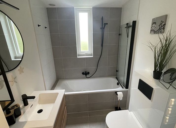 Charming exterior of vacation home Zeelandmuschel in Den Osse, Schouwen-Duiveland, surrounded by green nature and flowers.