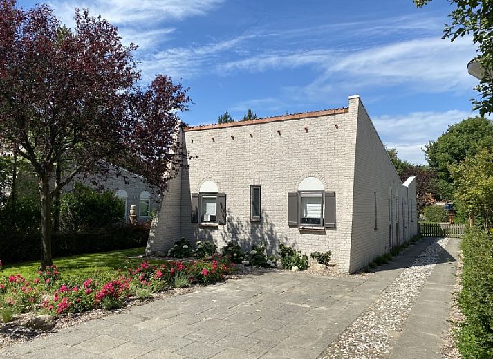 Charming exterior of vacation home Zeelandmuschel in Den Osse, Schouwen-Duiveland, surrounded by green nature and flowers.