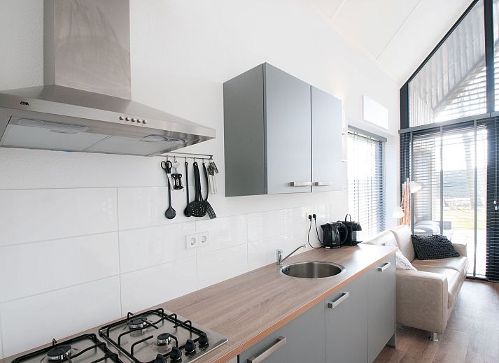 Strand am Ferienhaus Oesterdam Resort in Tholen, Zeeland mit Sonnenuntergang und Liegestuehlen.