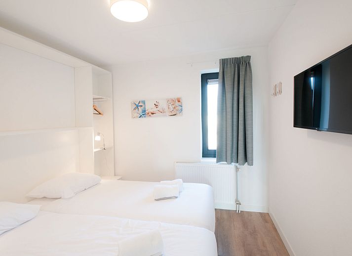 Strand am Ferienhaus Oesterdam Resort in Tholen, Zeeland mit Sonnenuntergang und Liegestuehlen.