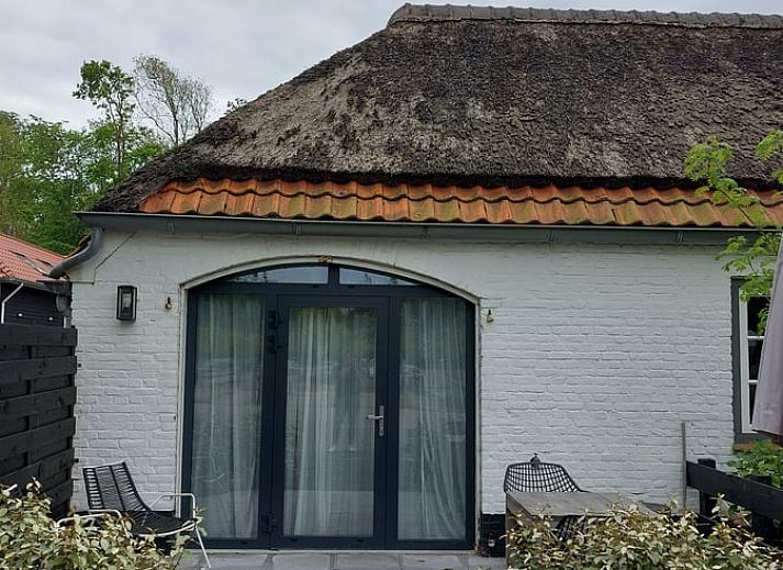 Charming cottage in Koudekerke, Walcheren, Zeeland with thatched roof and cozy outdoor area for a relaxing stay.