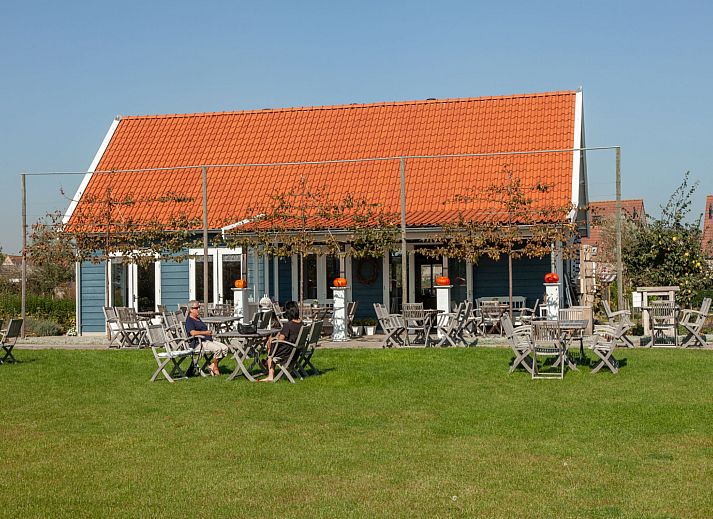 Aussenterrasse des Ferienhauses 'T Bloemenhof Koudekerke mit Holztischen und Stuehlen, Walcheren, Zeeland.