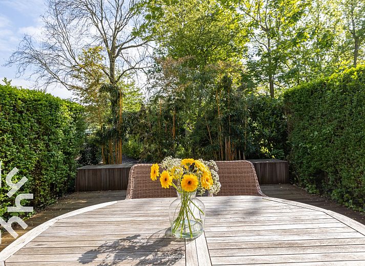 Veranda des Ferienhauses ZE744 in Oostkapelle, Walcheren, Zeeland mit Holztisch und Korbsesseln.