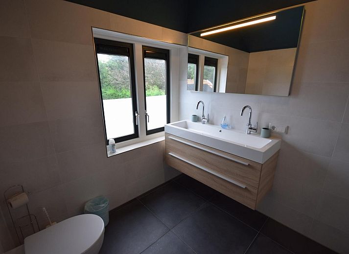 Hoelzerner Picknicktisch im Garten des Ferienhauses VZ1158 in Oostkapelle, Walcheren, umgeben von Gruenflaechen.