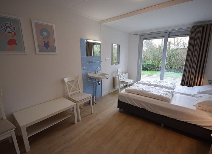 VZ1169 Ferienbungalow in Oostkapelle mit gepflastertem Innenhof und gruenen Hecken.