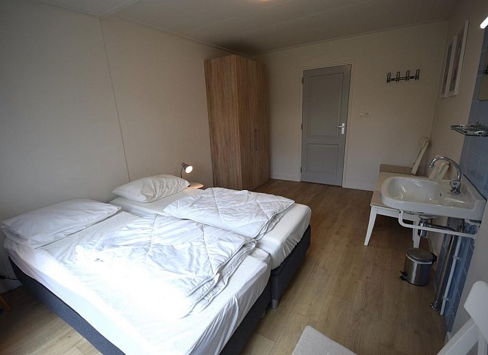 VZ1169 Ferienbungalow in Oostkapelle mit gepflastertem Innenhof und gruenen Hecken.