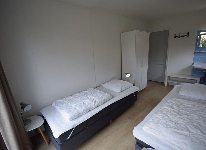 VZ1169 Ferienbungalow in Oostkapelle mit gepflastertem Innenhof und gruenen Hecken.