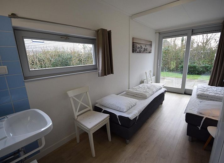 VZ1169 Ferienbungalow in Oostkapelle mit gepflastertem Innenhof und gruenen Hecken.