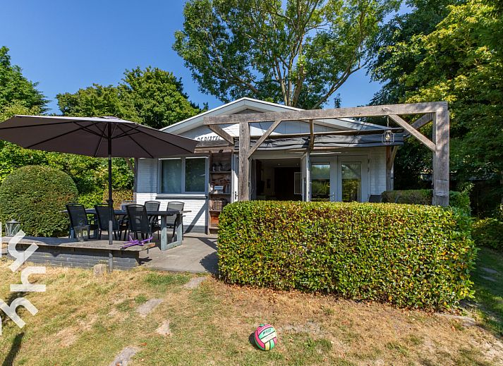 Veranda of vacation home ZE721 in Oostkapelle, Walcheren, with garden furniture and parasol.